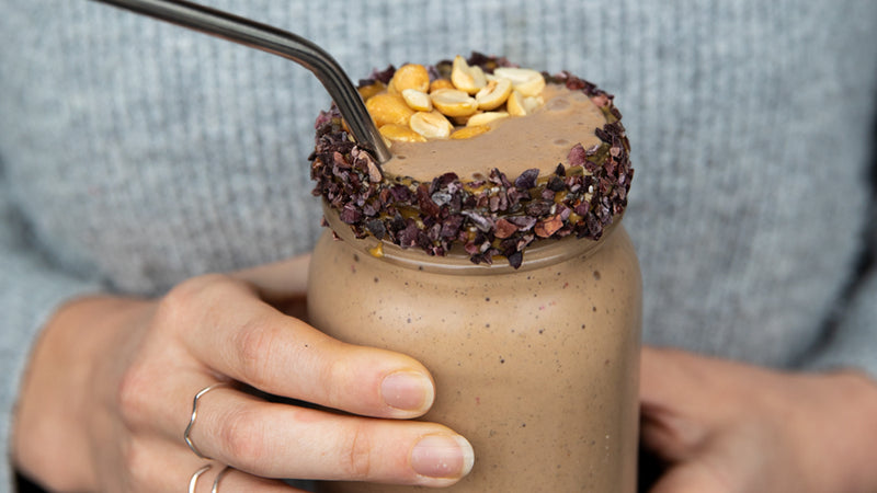 woman holding a gluten-free & vegan peanut butter smoothie jar